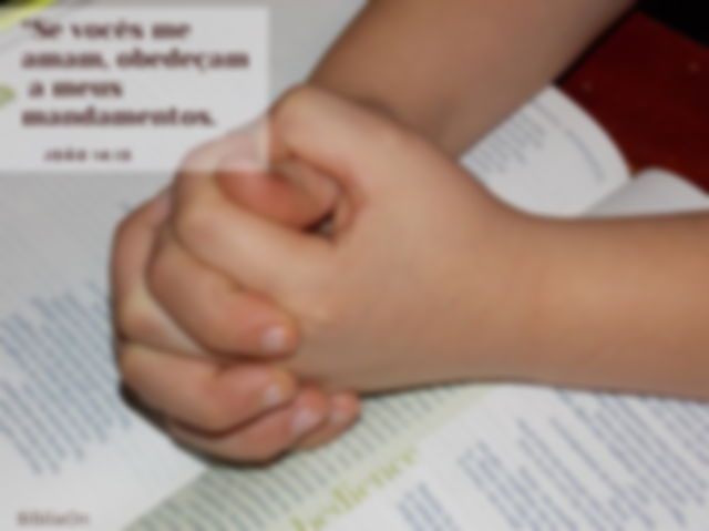 Criança - mãos entrelaçadas em oração sobre bíblia - João 14:15